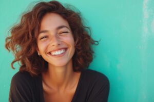 AdobeStock 1238076323 - Viera Dental Arts | Dentist in Melbourne FL A woman with curly hair is smiling and has her teeth showing