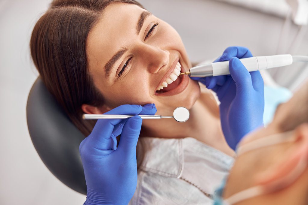 AdobeStock 428238505 - Viera Dental Arts | Dentist in Melbourne FL Female patient at dental procedure, doctor using dental instruments in modern dental clinic.