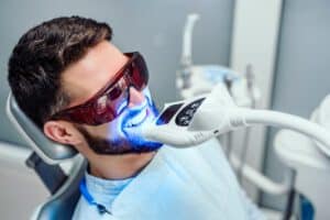 AdobeStock 265971927 - Viera Dental Arts | Dentist in Melbourne FL Dentist starting teeth whitening procedure with young man.
