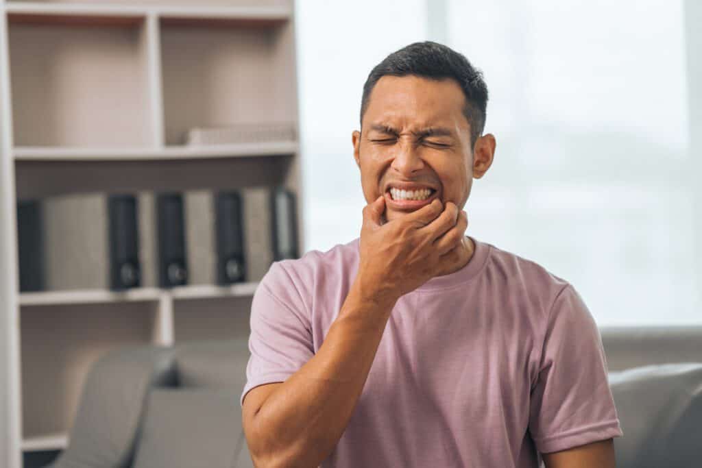 AdobeStock 658527076 - Viera Dental Arts | Dentist in Melbourne FL Middle-aged Asian Indian man with gum disease, toothache, wisdom tooth and molar pain. sitting on the sofa