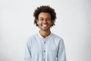 AdobeStock 151996745 - Viera Dental Arts | Dentist in Melbourne FL Handsome unshaven young dark-skinned male laughing out loud at funny meme he found on internet, smiling broadly, showing his white straight teeth. Positive human facial expressions and emotions